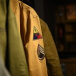 Detailed view of a military-style jacket featuring unique patches on the sleeve, emphasizing vintage style.