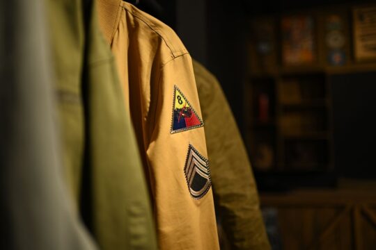 Detailed view of a military-style jacket featuring unique patches on the sleeve, emphasizing vintage style.